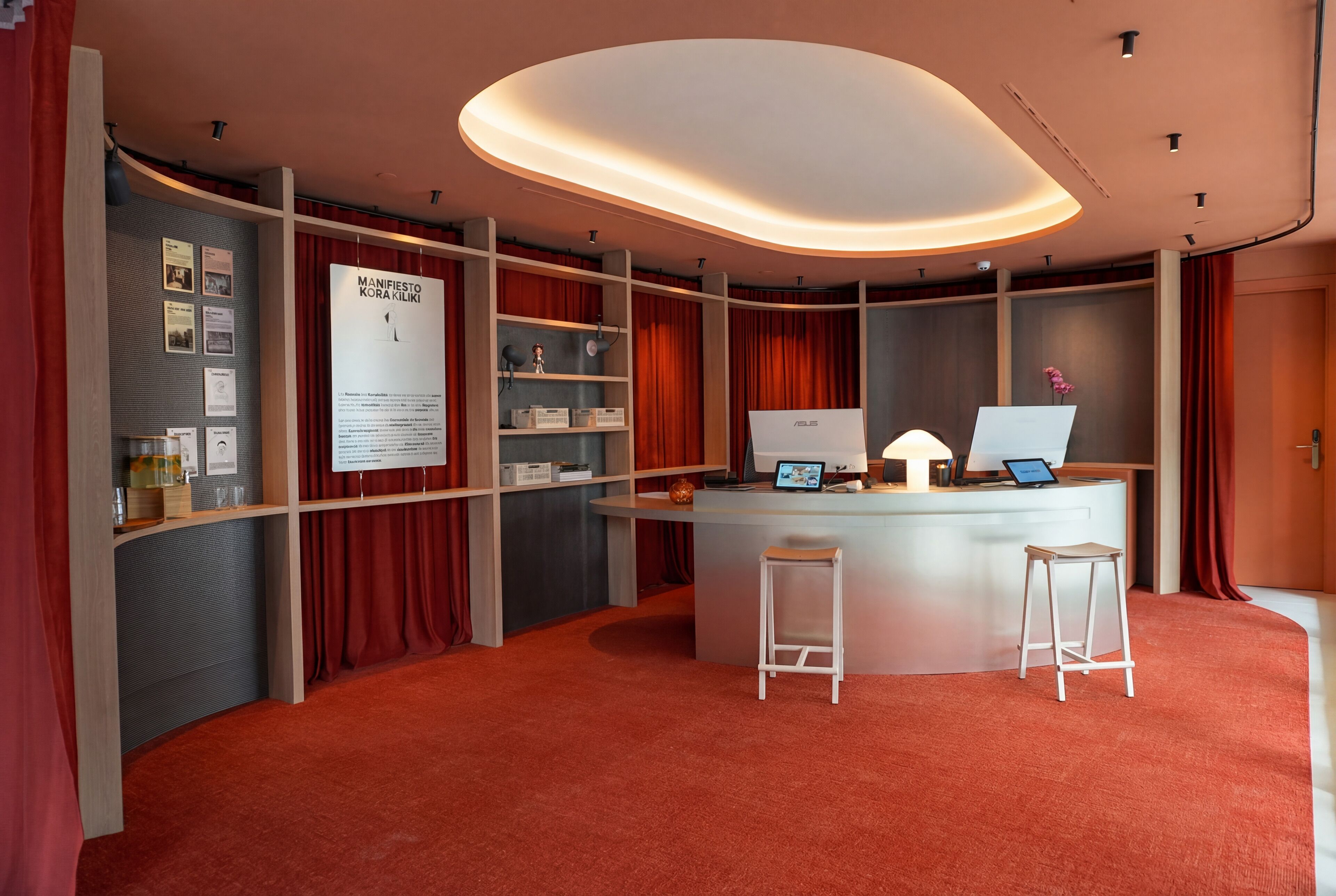 A modern reception area with a curved ceiling, a desk with a laptop, and a bulletin board with various notices.