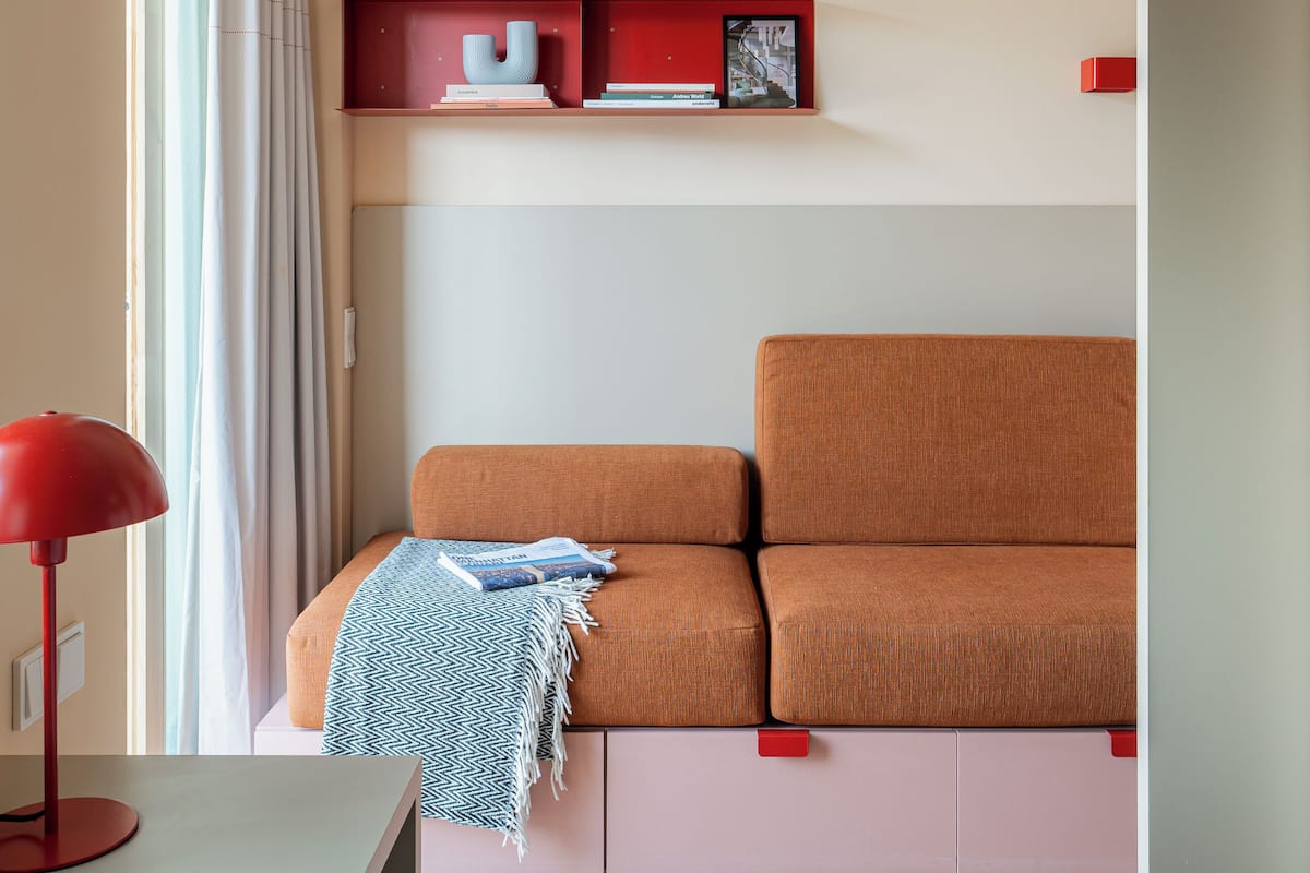 A modern room with a sofa, a desk, and a red lamp.