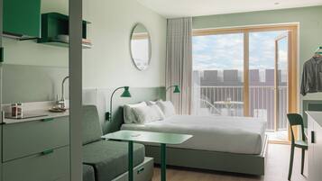 Habitación de hotel moderna con cama, escritorio, silla y balcón con vista a la ciudad.