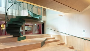 A modern interior with a spiral staircase, wooden steps, and a glass railing. - KORA KILIKI (Pamplona)