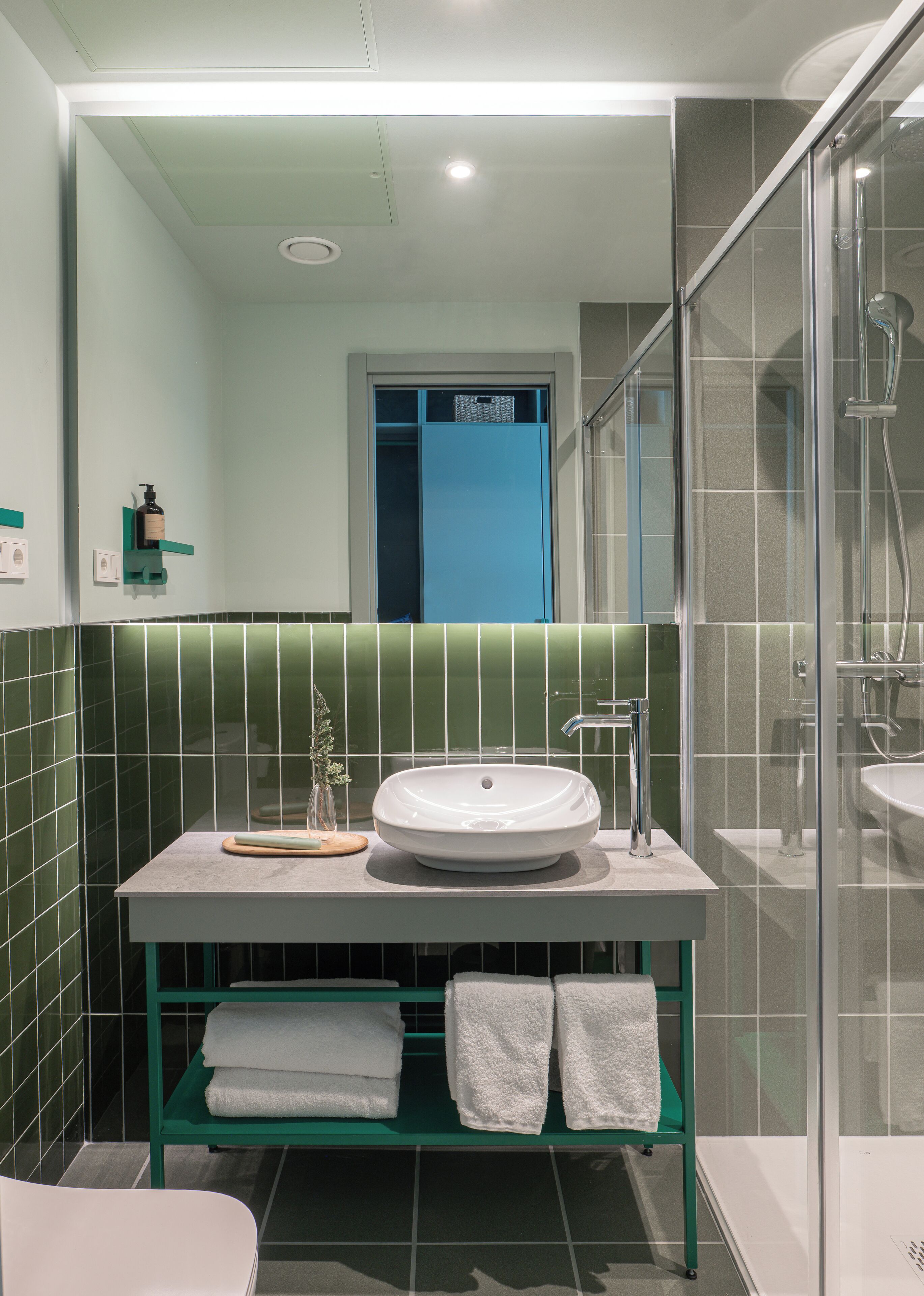 A bathroom with a white sink, green towel rack, and a shower area.