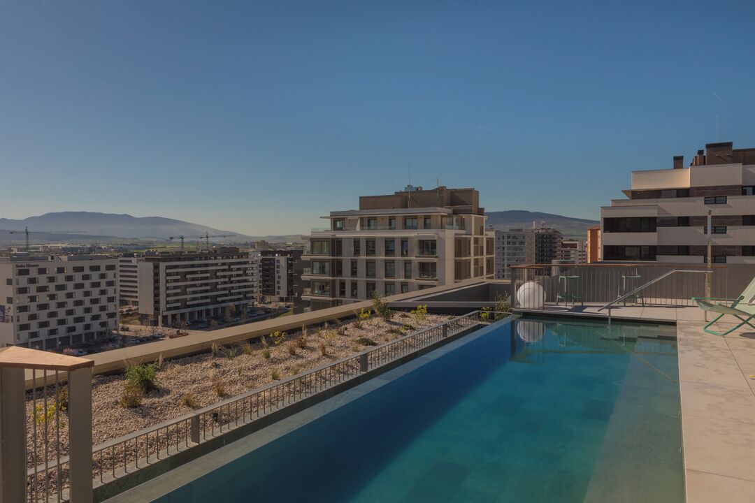 Una piscina en la azotea con vistas despejadas de edificios y montañas circundantes.