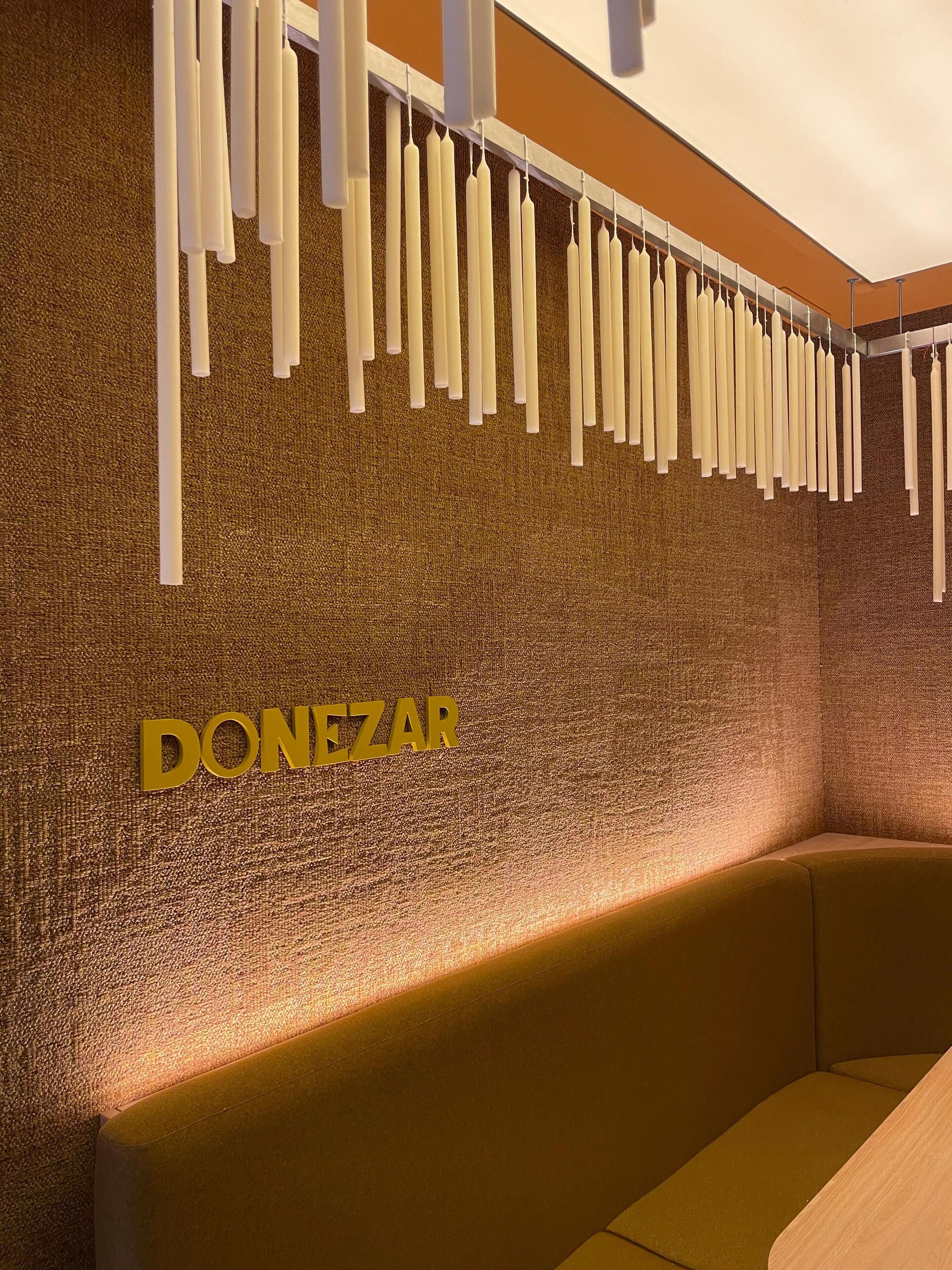 Un mur orné d’objets blancs suspendus et sur lequel on peut lire le mot « DONEZAR » en lettres dorées.
