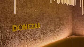 Een muur met hangende witte objecten en de tekst 'DONEZAR' in gouden letters.