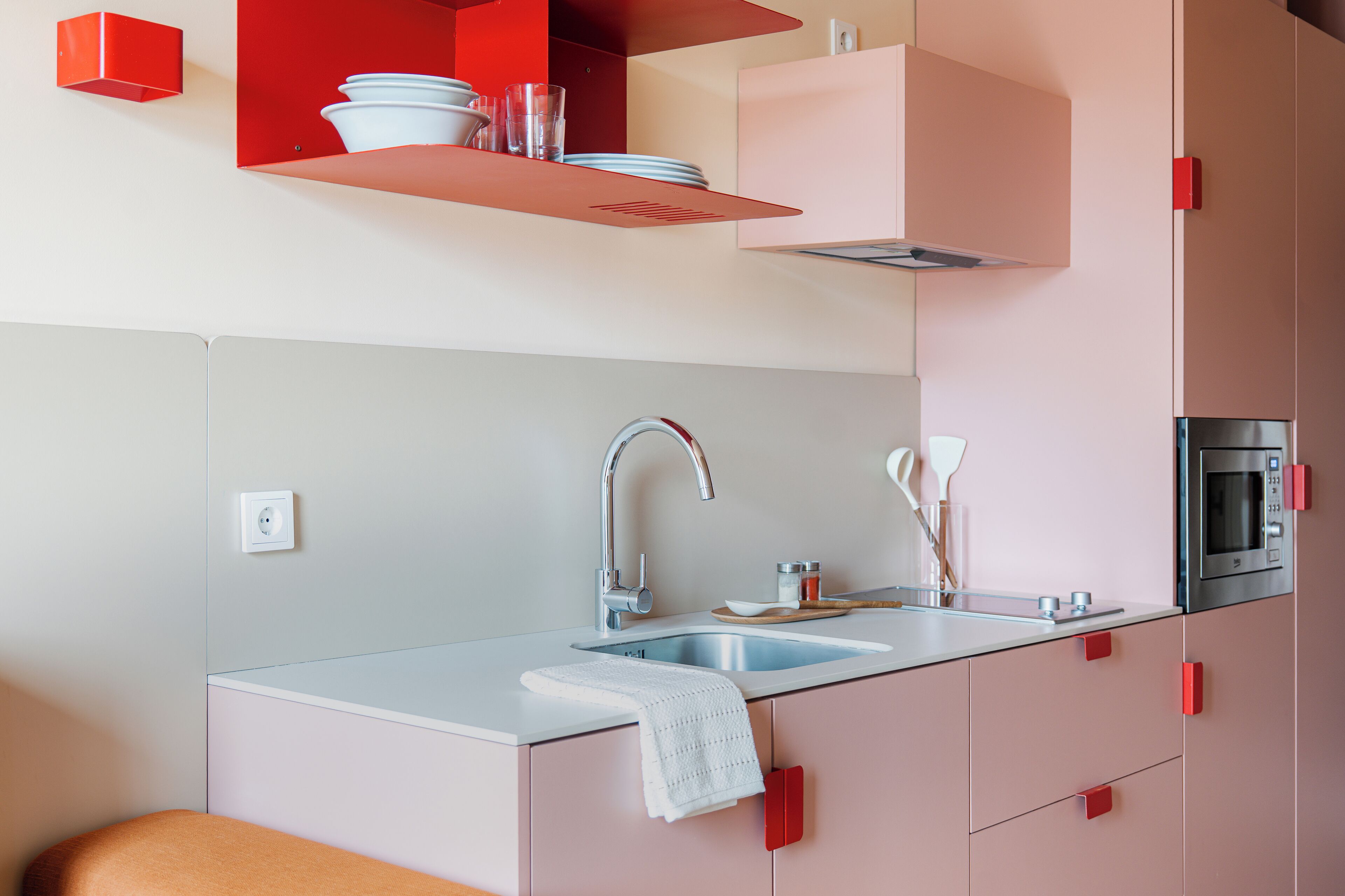 Una cocina moderna con un lavamanos doble, electrodomésticos de acero inoxidable y armarios color rosa.