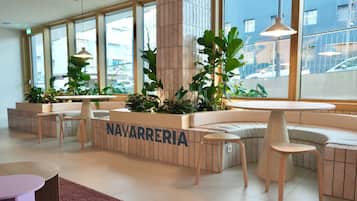 A modern, well-lit lobby with seating areas, large windows, and indoor plants.