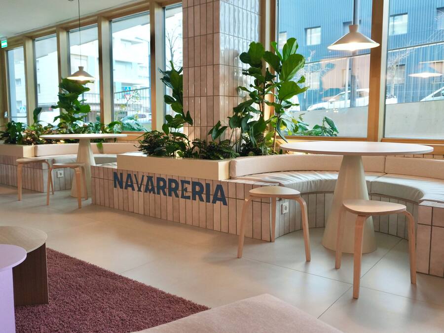 A modern, well-lit lobby with seating areas, large windows, and indoor plants.