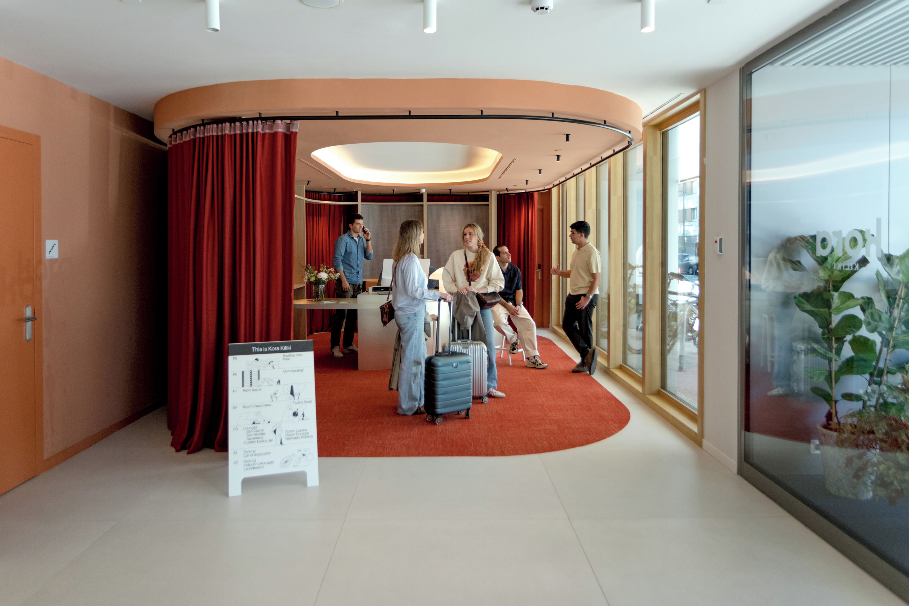 Een hotel lobby met een gebogen rood tapijt, een receptiebalie en een groot raam met uitzicht.