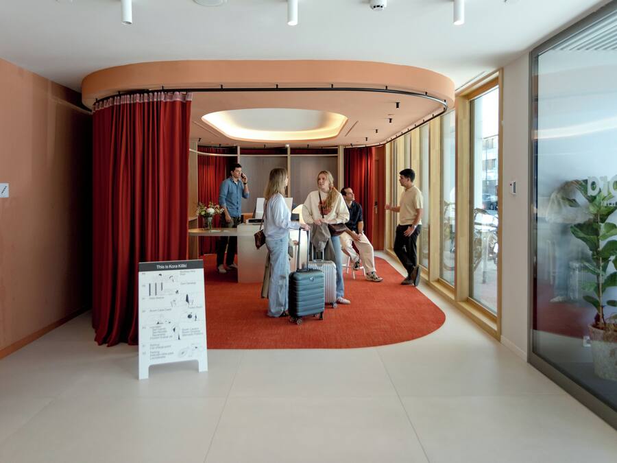 A hotel lobby with a curved red carpet, a reception desk, and a large window with a view.