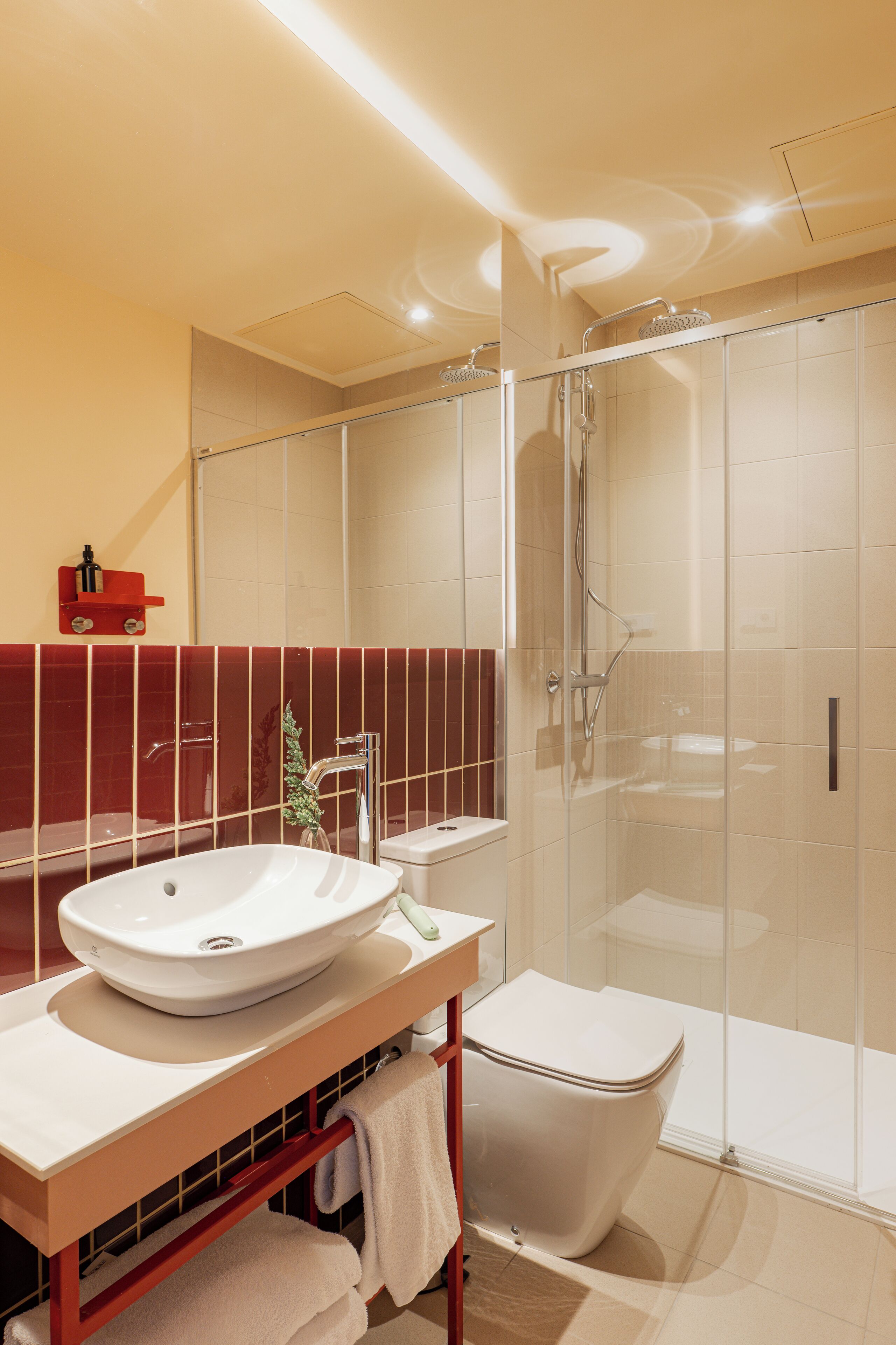 Un baño moderno con ducha de vidrio, un lavabo blanco y un inodoro.