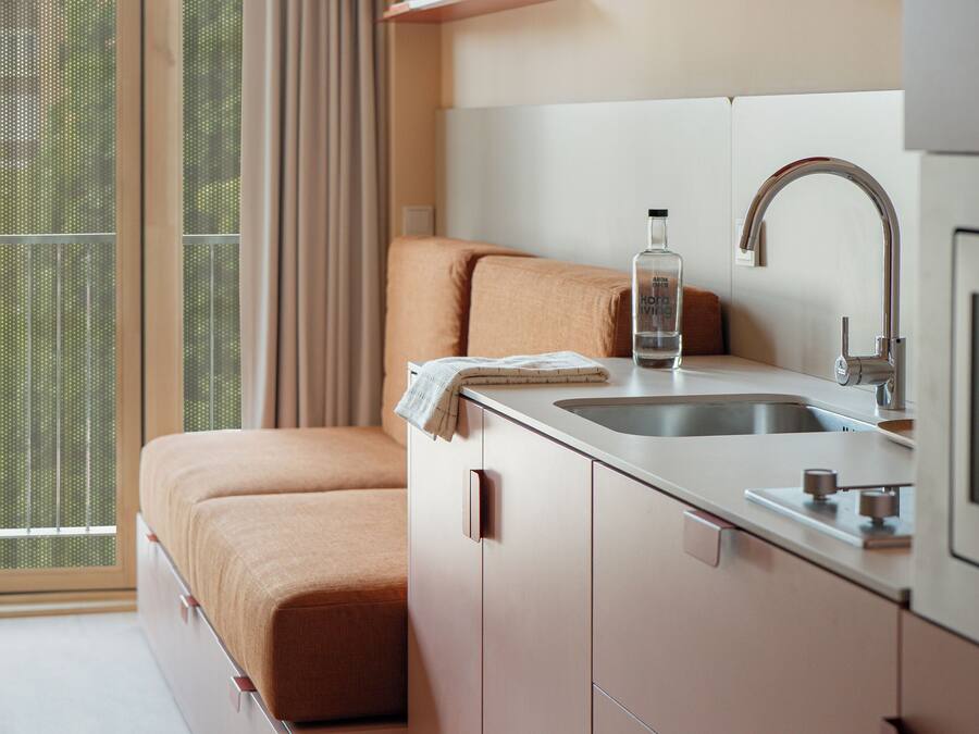 Een kleine kamer met een bed, een wastafel en een raam met gordijnen.