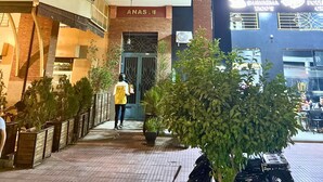 A multi-story building with a brick facade, a visible entrance with a door, and a sign above the entrance. - Apartment Marrakech Menara (Marrakesh)