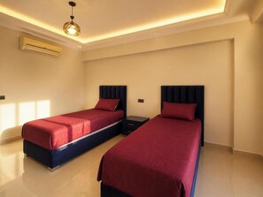Un dormitorio con dos camas, cada una con cabecera y colcha roja.