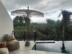 En balkon med havudsigt, en pool og udendørs møbler.