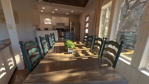 Uma sala de jantar com uma mesa comprida, cadeiras e um vaso de planta.