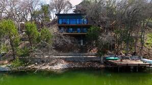 Um edifício de vários andares com um cais e piscina inflável à beira da água.