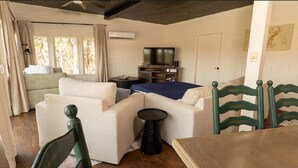 Um quarto aconchegante com sofá, mesa pequena, televisão e cama.