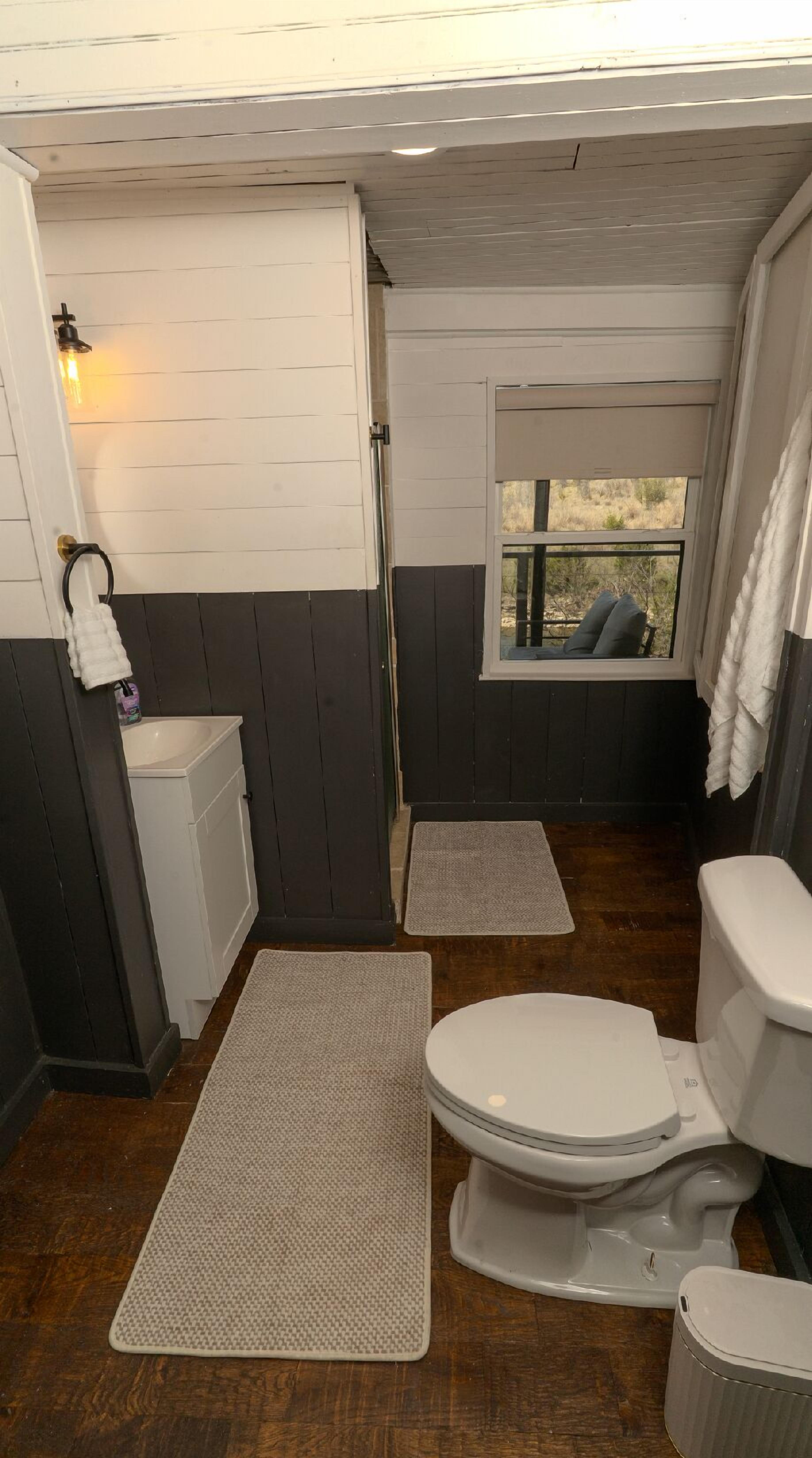 A bathroom with a toilet, sink, and window.