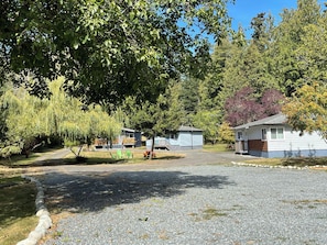 A campground with two mobile homes, a picnic table, and a gravel driveway.