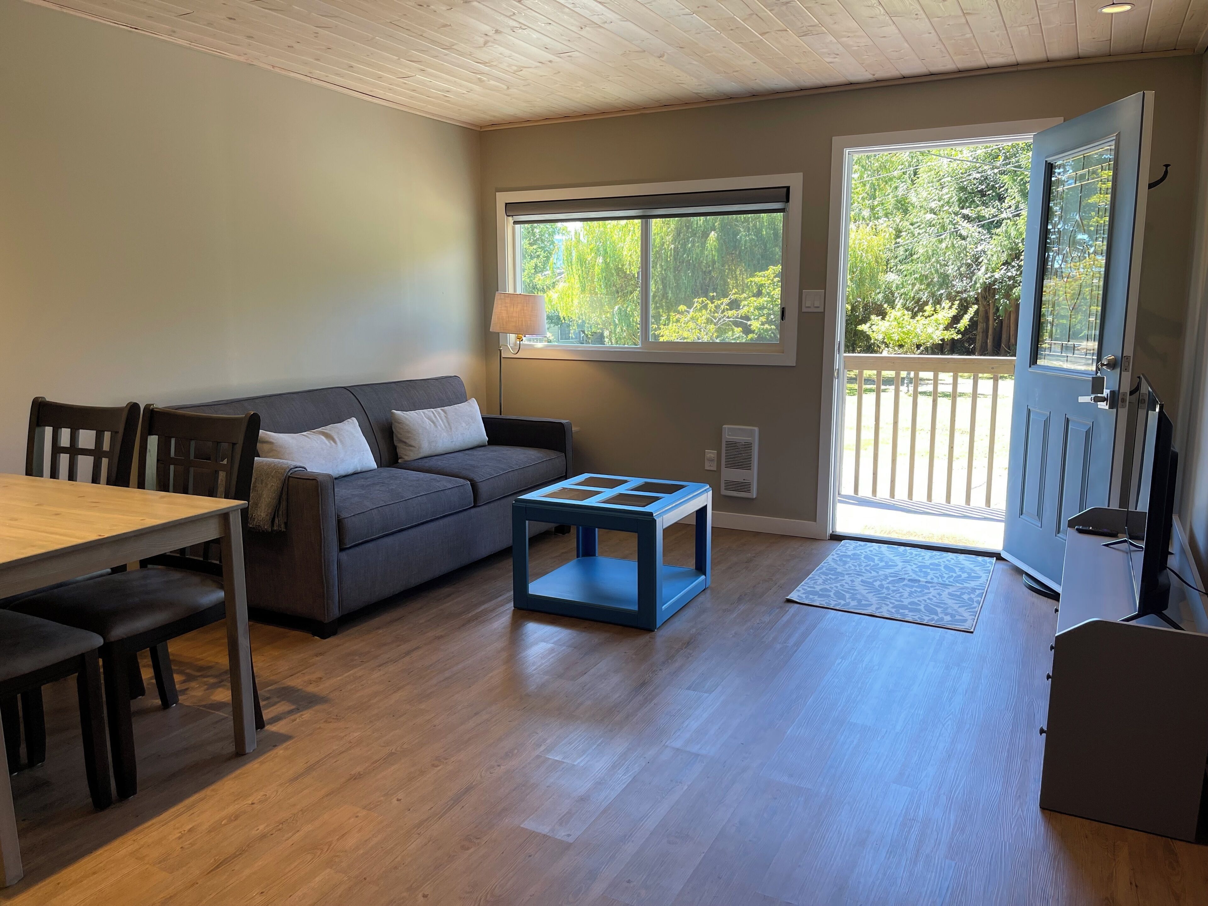 A cozy living room with a sofa, a coffee table, and a dining table.