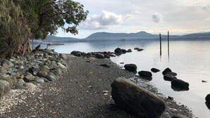 En strand med småsten och stora stenar, och ett träd till vänster.