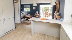 Une cuisine moderne dotée d’un îlot central, de planchers en bois et de luminaires suspendus.