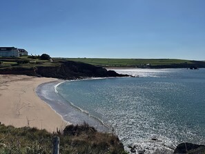 A coastal landscape with a sandy beach, a clear blue sea, and a grassy hill with a building in the background. - Thurlestone, 1 Island View (Kingsbridge)