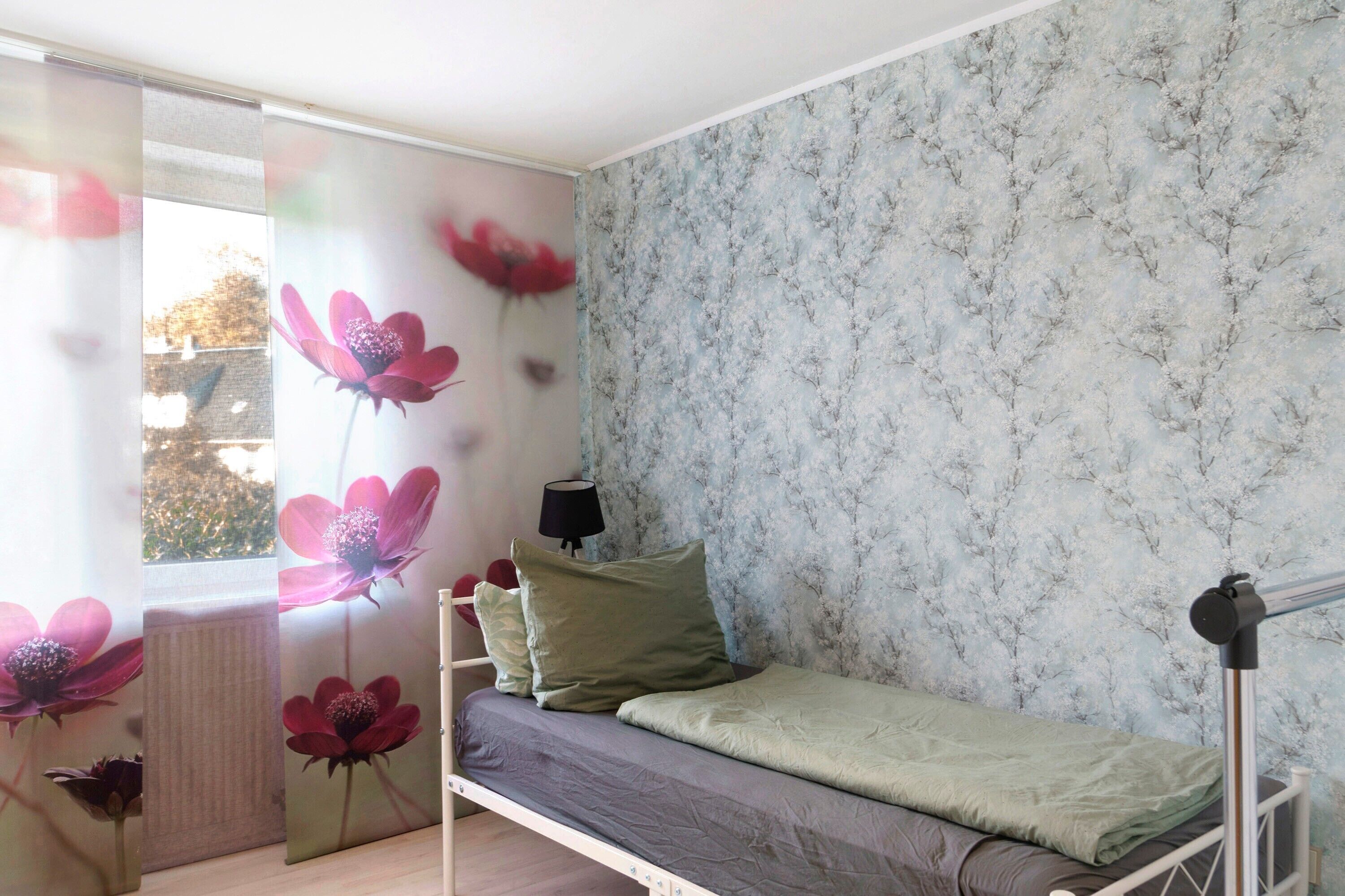 A bedroom with a bed, pillows, a lamp, and a window with curtains.