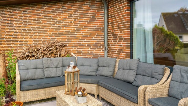 A corner sectional sofa with cushions, a lantern, and a small table with decorative items.