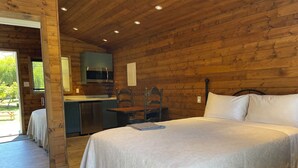 A wooden cabin with a bed, a dining table, and a kitchenette. - Two Cottage units (duplex) on Waterfront Property with Beach Access - Sleeps 4 (Sooke)