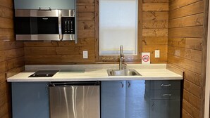A compact kitchen with wooden walls, a stainless steel microwave, a dishwasher, and a sink. - Two Cottage units (duplex) on Waterfront Property with Beach Access - Sleeps 4 (Sooke)