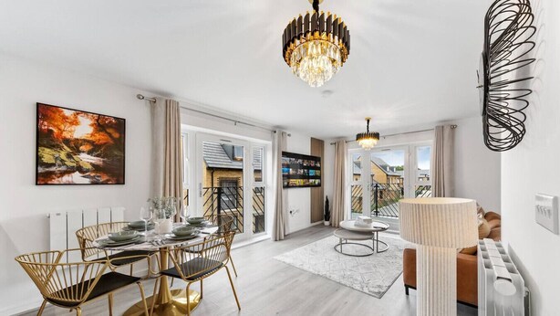 A modern dining area with a round table, gold chairs, and a chandelier. - Brandnew Luxurious 2bedApartment (Ebbsfleet Valley)