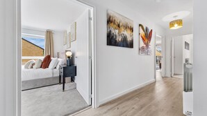 A modern hotel room with a bed, bedside table, lamp, and artwork on the wall. - Brandnew Luxurious 2bedApartment (Ebbsfleet Valley)