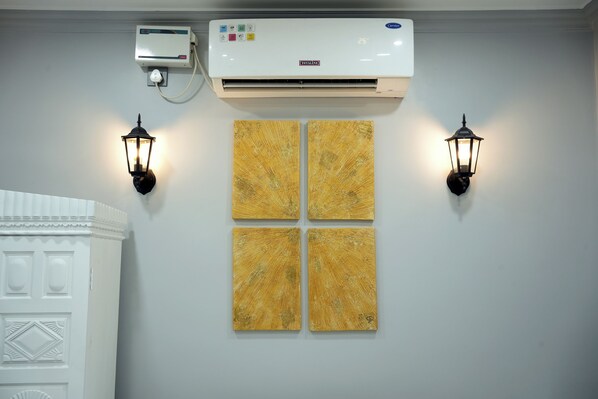 A wall-mounted air conditioner, two wall-mounted lanterns, and four square paintings.