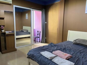 A bedroom with a bed, a desk, a chair, and a sliding door leading to a balcony.