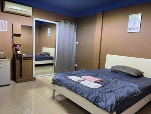 A bedroom with a bed, a bedside table, a mirror, a wardrobe, and a poster on the wall.