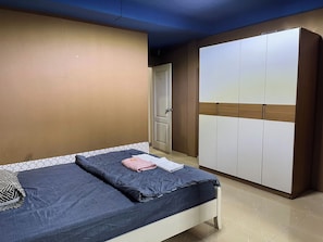A bedroom with a bed, a wardrobe, and a door.