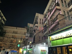 A street view at night with buildings, a sign for 'Rivana Bo' restaurant, and a 'Taxi Service' sign.