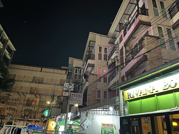 A street view at night with buildings, a sign for 'Rivana Bo' restaurant, and a 'Taxi Service' sign.