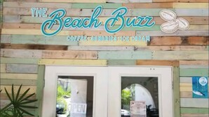 Een winkelgevel met een bord waarop staat 'The Beach Brrr' en een menu met koffie, snuisterijen en ijs.