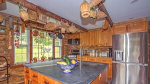 A kitchen with wooden cabinets, a stainless steel refrigerator, and a bowl of fruit on the counter. - Charming Barn Home Near Jiminy Peak (Hancock)
