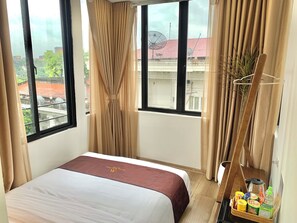 A hotel room with a bed, curtains, a window with a view, and a small table with snacks. - Maison Maravelle Hotel (Ha Noi)