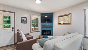 A living room with a brown sofa, a light-colored sofa, a fireplace, and a door with a window.