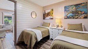 A room with two beds, a dresser, a mirror, and a painting of a fish on the wall.