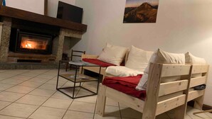 Una stanza accogliente con un camino, un letto di legno, un tavolino e un quadro appeso al muro.