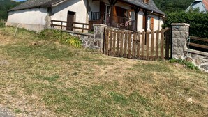 Un tipico chalet con facciata in pietra, balcone in legno e cortile recintato.