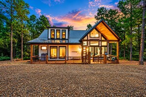 A two-story lodge with a covered porch, large windows, and a stone-paved entrance.