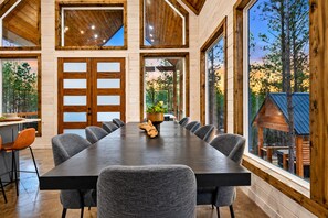 A large conference table with chairs, a wooden door, and large windows with a view of trees.