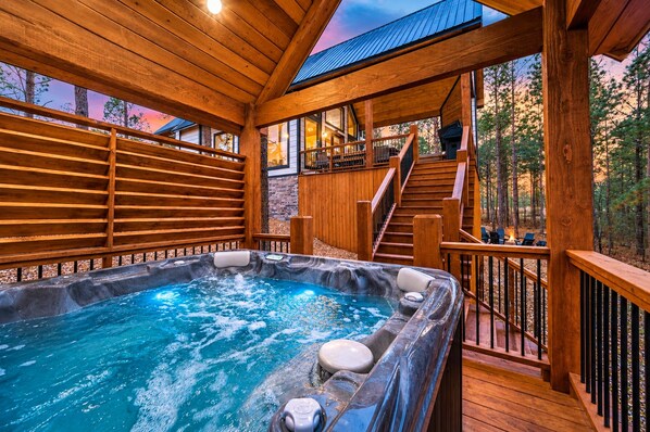 A hot tub with a wooden deck and a staircase leading to an upper level.
