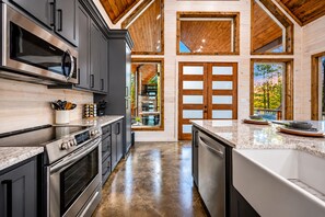 A modern kitchen with dark cabinetry, stainless appliances, and a large island.